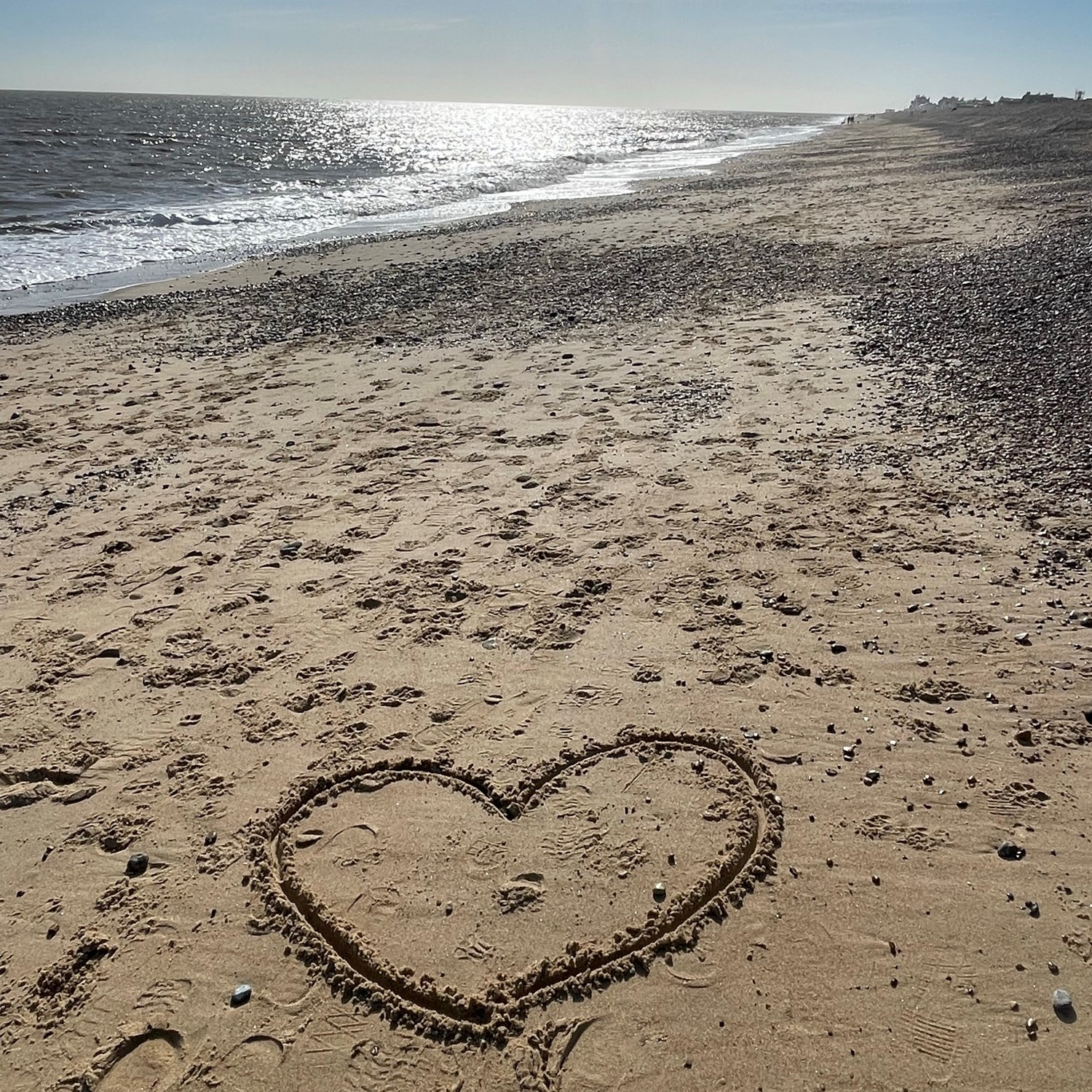 A heart inscribed in the sand of a sunlit beach