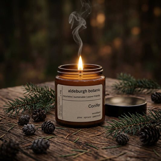 Aldeburgh Botanic Conifer woodland candle with a lit wick surround by pine cones and spruce
